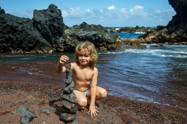 小石を作る子供は海のそばの火山岩に積まれています。禅の概念. — ストック写真
