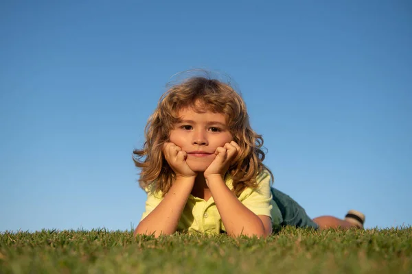 Ritratti di bambini felici che giocano e si sdraiano sull'erba all'aperto nel parco estivo. divertente bambino faccia all'aperto. — Foto Stock