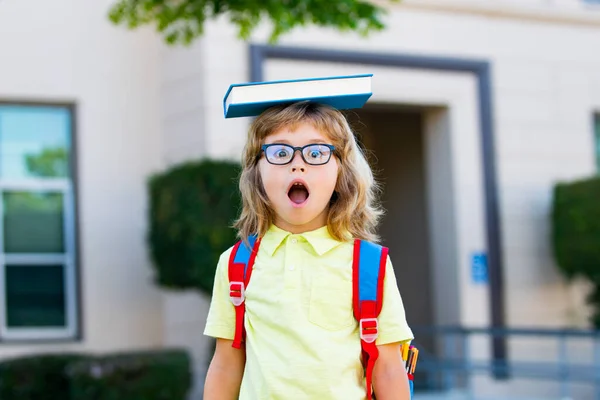 큰 가방 과 책을 들고 학교에 대하여 재미있게 놀고 있는 쾌활 한 소년. 학교로 돌아가. 교육 과읽기에 대한 개념. — 스톡 사진