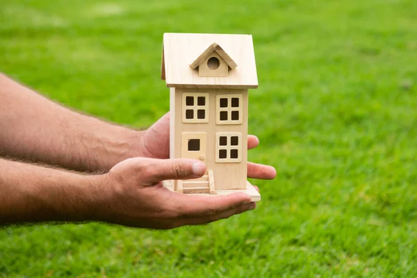 Mano sosteniendo la casa de juguete de cerca. Pequeña casa de juguete en miniatura. Hipoteca propiedad sueño mudanza casa y concepto de bienes raíces. — Foto de Stock