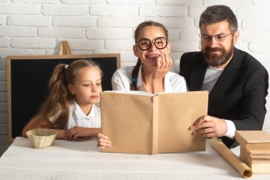 Babam tatlı liseli kızlarla eğleniyor. Baba ve küçük çocuklar. Aşk ailesi, öğretmenler günü ebeveynlik kavramı. Kitap okunuyor.