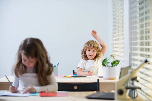 Educação, aprendizagem e conceito de pessoas. Menina estudante com livro escrita teste da escola. De volta à escola. criança bonito feliz está sentado em uma mesa dentro de casa. — Fotografia de Stock