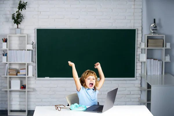 Opgewonden schoolkind leerling met laptop computer in de klas op school. — Stockfoto