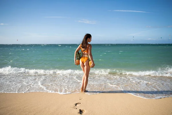 Female buttocks in swimsuit, sexy ass. Woman holding a pineapple on the dominican or hawaii beach tropical background with copyspace. — Photo