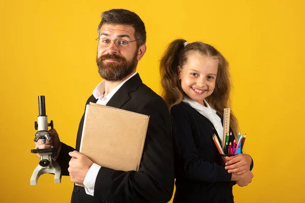 행복 한 학생 과 함께 선생님. 재미있는 여학생 과 교사가 학교 용품을 가지고 있는 모습. 노란색 옷을 입은 행복 한 교사와 학생 소녀. 학교로 돌아가서, 제복을 입은 여학생. — 스톡 사진