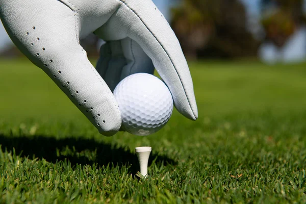 Hand setzt Golfball auf Abschlag im Golfplatz. Golfball im Gras. — Stockfoto