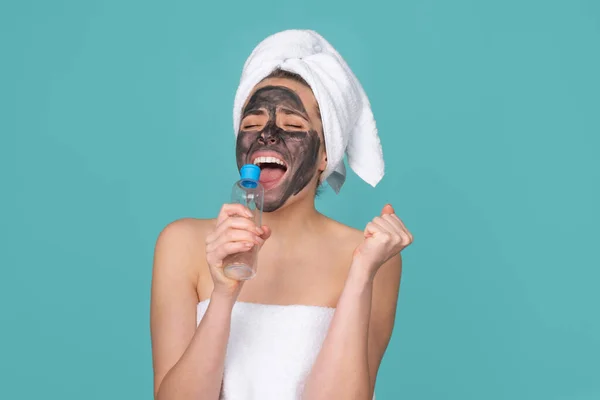 Mujer hermosa excitada con procedimiento facial de barro cosmético, concepto de salud spa. Tratamiento de belleza del cuidado de la piel. Toalla en la cabeza. Barro mineral médico. — Foto de Stock