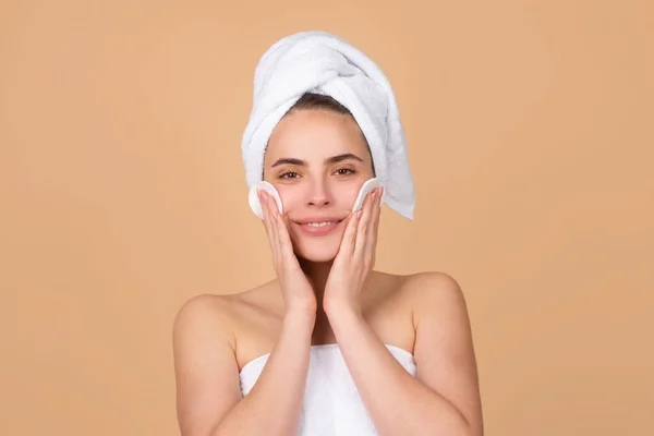 Ansiktsbehandling. Kosmetologi skönhet och spa. Flicka tillämpa hudvård grädde i ansiktet, kvinna linda handduk på huvudet sätta ansiktskräm på gör morgonen frisk hud. — Stockfoto