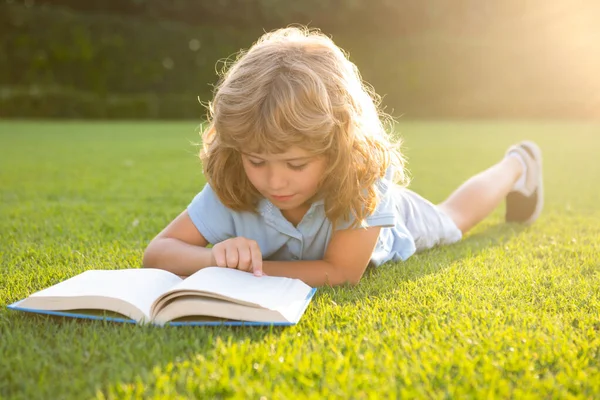 Inteligentes niños inteligentes. Niño relajarse en las vacaciones. Niño leer libros sobre hierba fondo. — Foto de Stock