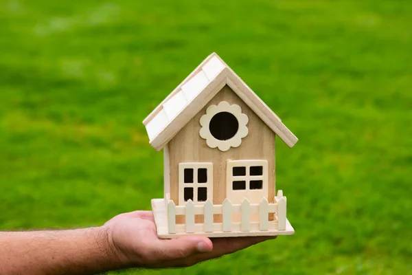 Manos masculinas sosteniendo una pequeña casa de juguetes en miniatura. Hipoteca propiedad de seguros sueño de mudarse a casa y el concepto de bienes raíces. Seguro de hogar. Casa nueva. — Foto de Stock