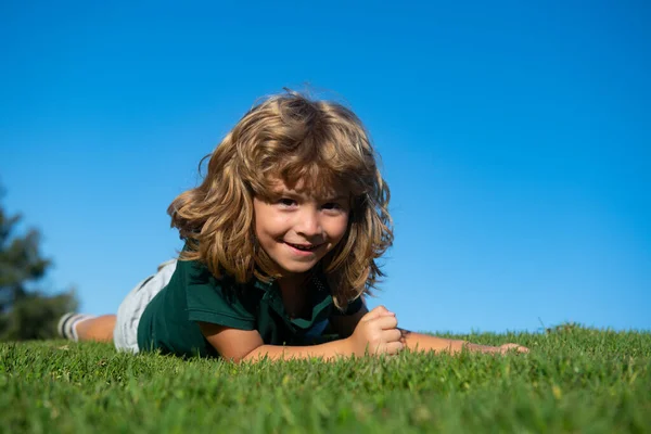 Portret van een lachend kind op groen gras. Leuke jongen die buiten van de natuur geniet. Gezond zorgeloos kind dat buiten speelt in het zomerpark. — Stockfoto