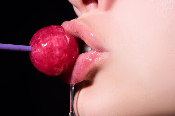 Концепция оргазма. Леденец во рту женщины, красная помада. Женщина лижет красный блестящий леденец. Закрывай. Сексуальная женщина с леденцом во рту.