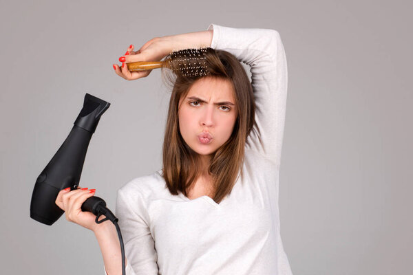 Woman with hair dryer. Beautiful girl with straight hair drying hair with professional hairdryer. Haircare concept.