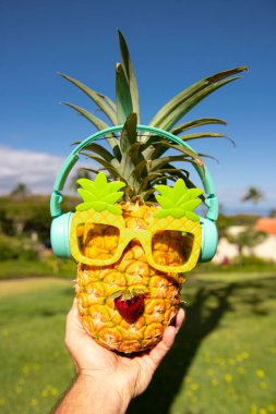 Yaz tropik ananas arka planı. Ananas güneş gözlüklü, mavi gökyüzü arka planında bir palmiye ağacının altında. Plajda kokteyl partisi, dinlenme, rahatlama ve yaz konsepti..
