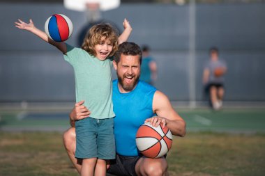 Babasıyla basketbol oynayan tatlı çocuk. Baba ve çocuk birlikte vakit geçiriyorlar. Baba ve oğul dışarıda oynuyorlar..