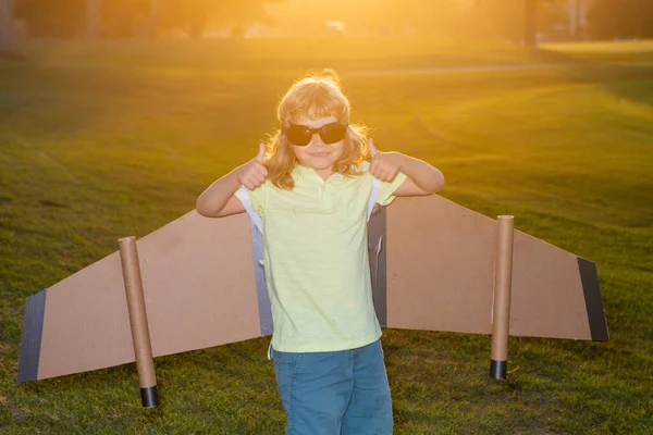 Vit unge leker med leksaksplan på solig gyllene solnedgång himmel bakgrund utanför på gräsbevuxen sommar kulle vid solnedgången. Drömmer om lycklig framtid koncept. — Stockfoto