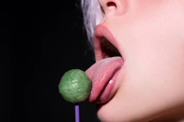 A lamber lábios de língua. Menina com boca sexy comendo chupa chups de perto. Lábios de mulher chupando pirulito. Mulher segurando pirulito na boca, de perto. Lábios vermelhos, conceito sensual e sexy. — Fotografia de Stock