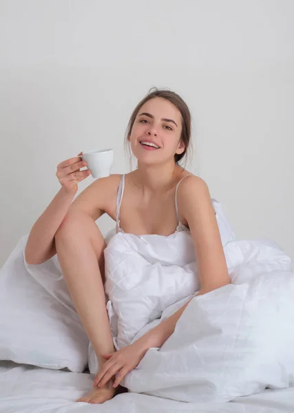 Eautiful young woman awakening in bed with cup coffee. Ευτυχισμένος ξυπνήστε και ξεκινήστε τη νέα ημέρα. Αναψυχή και ξεκούραση. Ευεξία έννοια. — Φωτογραφία Αρχείου