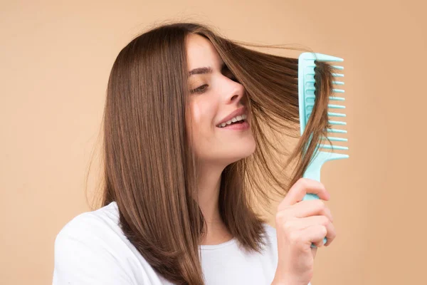 Hermosa mujer peina su cabello sano. Peinar el cabello largo y largo femenino sano, de cerca. Atractiva hermosa alegre chica positiva peinando brillo cabello sedoso, aislado. —  Fotos de Stock