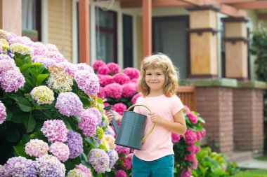 Arka bahçedeki çocuk suları, sulama tenekesiyle..