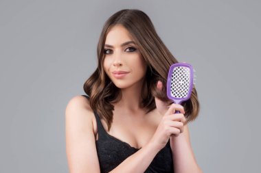 Tarakla saçlarını tarayan bir kadın. Saç fırçasıyla uzun, sağlıklı saçları tarayan bir kız. Saç bakımı güzellik konsepti. Saç fırçalama.