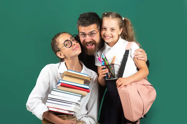 Retrato do pai e da escola crianças filhas abraçando no fundo quadro negro. A ler livros e a escrever. Pai ensinando meninas da escola em sala de aula. — Fotografia de Stock