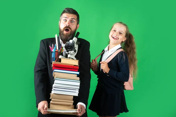 Vater führt seine Schülerin zur Schule. Porträt eines modernen Familienvaters und kleiner Mädchen isoliert auf grünem Hintergrund. — Stockfoto