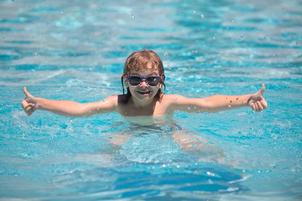 Chłopak pływa w basenie. Podekscytowane dziecko w okularach słonecznych w basenie w letni dzień. — Zdjęcie stockowe