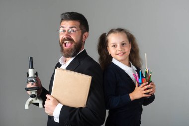 Heyecanlı, mutlu bir öğrenci kız öğrenci ile harika bir öğretmen. Komik liseli kız portresi ve okul malzemeleriyle özel öğretmen. Gri elbiseli mutlu öğretmen ve öğrenci kız. Okula dön, üniformalı kız..