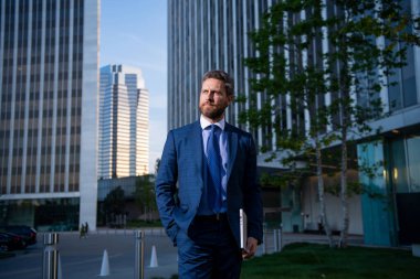 İş adamının elinde dizüstü bilgisayar vardı. İş yerinin yakınında duruyordu..