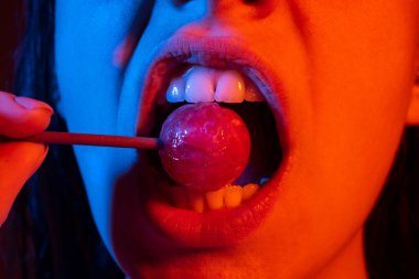 Cazibeli ağız kırmızı dudaklı lezzetli lolipopları yalıyor. Lolipop berbat. Seksi kadın dudağı. Lolipopu olan şehvetli, kırmızı dudaklı bir kadın. Çikolata konsepti.