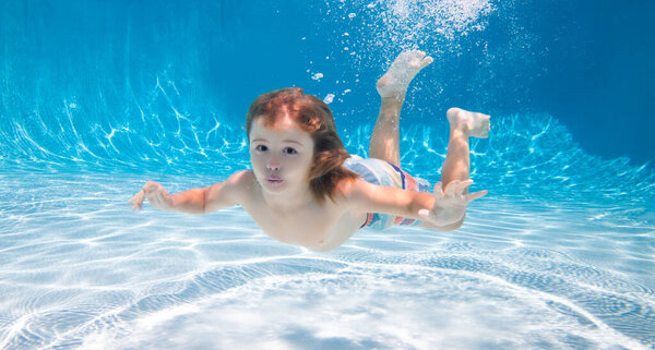 Underwater child swim under water in swimming pool.