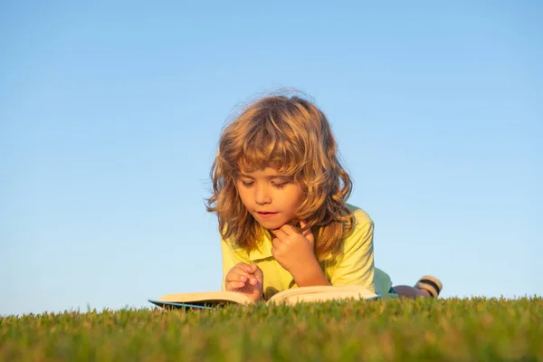 Barn fantasi, innovation och inspirationsbarn. Utomhus porträtt av liten pojke läser en bok. — Stockfoto