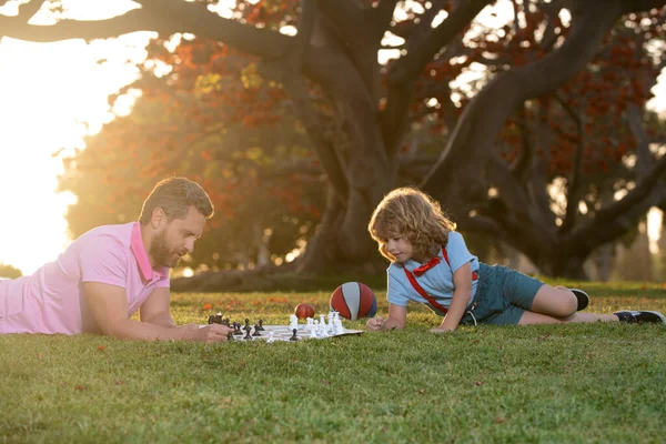Pai e filho jogando xadrez passar o tempo juntos no parque. Jogos e entretenimento para crianças. Conceito familiar. — Fotografia de Stock