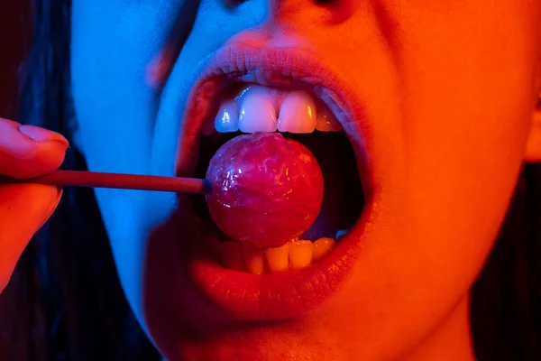 Glamour boca lamiendo deliciosa piruleta con labios rojos. Apesta el pop lolli. Sexy labio femenino. Sensual mujer labios rojos con una piruleta. Concepto de barra de caramelo. — Foto de Stock