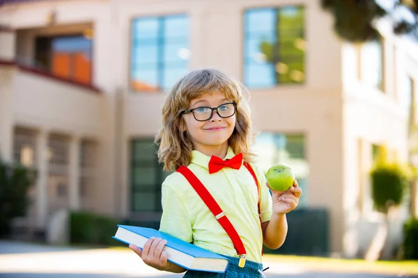 Jeune élève d'âge préscolaire portant sac à dos et livres près de l'école en plein air. — Photo