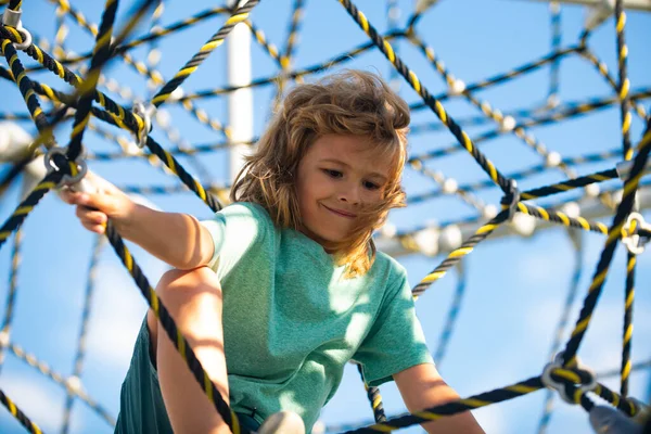 Portrait of cute boy child doing rock climbing in the playbackground. Little kid hanging on the monkey bar by his hand to exercise at outdoor playground. — Stock Photo, Image