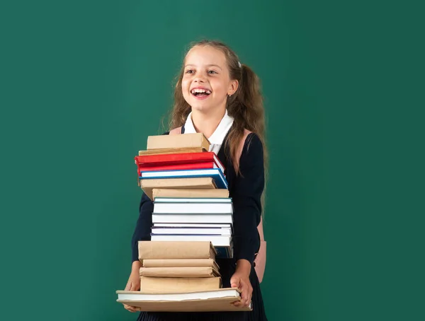 Boldog tizenéves iskolás gyermek tart könyveket zöld háttér, tudásnap. — Stock Fotó