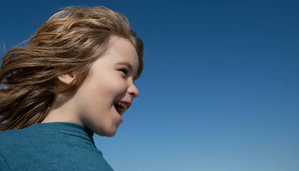 Niño excitado mirando hacia otro lado y gritando en el cielo azul con espacio de copia. Cara de niño, retrato de niño. —  Fotos de Stock