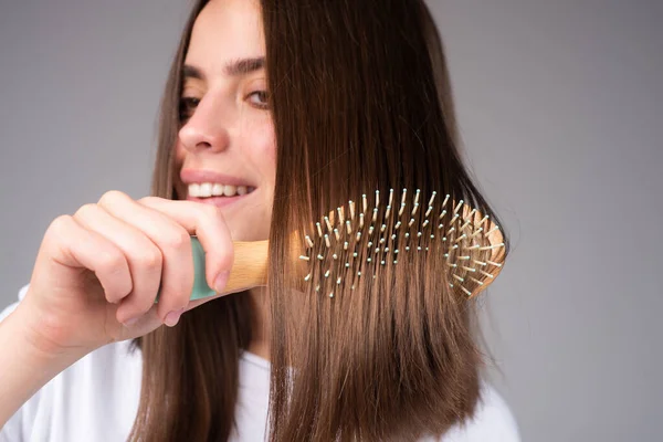 Sluit een vrouw die haar kamt. Haarverzorging. Mooie brunette haarborstel met haarborstel. Gezond haar borstelen met kam. — Stockfoto