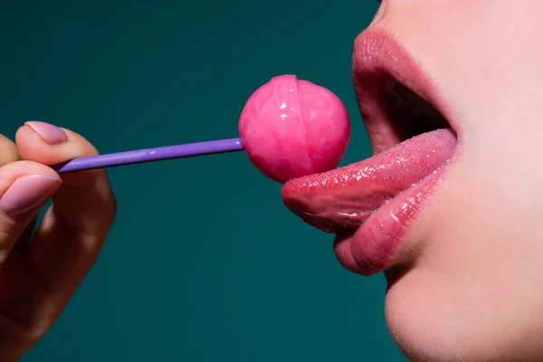 唇を舐めて。赤い唇でおいしいロリポップを舐めるグラマー口。ロリポップを吸う。セクシーな女性の唇。官能的な女性はロリポップと赤い唇。キャンディーバーのコンセプト. — ストック写真