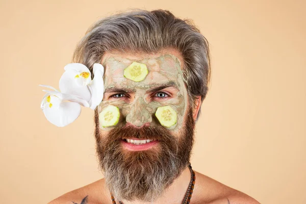 Yüzünde salatalık dilimleri olan komik bir adam. Spa, cilt bakımı, sağlık ve yüz bakımı konsepti. Adamın kozmetik nemlendirici maskesi ve izole edilmiş bir stüdyo geçmişi var. Erkek yüz bakımı. — Stok fotoğraf