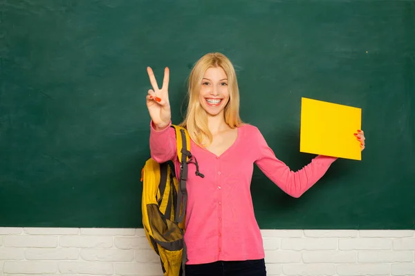 黒板の教室で女教師をしている。クラスの女子大生。製品のために空の紙を持っている学生の女の子. — ストック写真