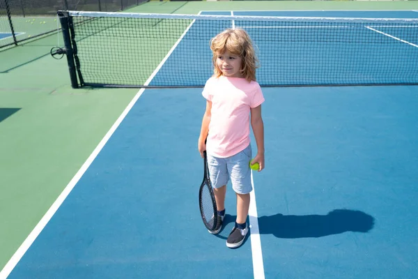 Niño con raqueta de tenis y pelota en pista de tenis al aire libre. Ejercicio deportivo para niños. Actividades de verano para niños. Niño aprendiendo a jugar tenis. —  Fotos de Stock