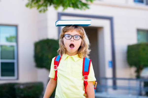 Jeune élève d'âge préscolaire portant sac à dos et livres près de l'école en plein air. — Photo