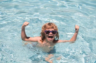 Yaz yüzme havuzunda bir çocuk. Güneşli bir günde, güneş gözlüklü, havuzda heyecanlı küçük bir çocuk..