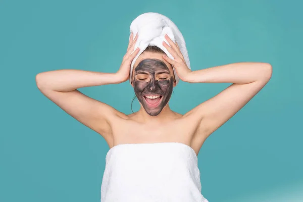 Vacker kvinna med kosmetisk lera ansiktsbehandling, spa hälsa koncept. Skönhetsbehandling av huden. Handduk på huvudet. Medicinskt minerallera. — Stockfoto