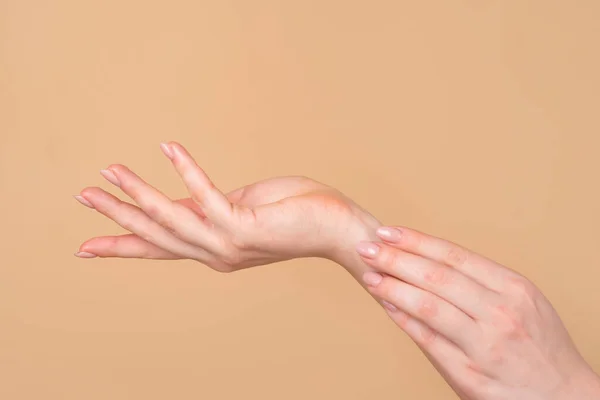Cuidado de las manos. Hermosas manos de las mujeres en el fondo beige. Hermosas manos de mujer con crema. — Foto de Stock