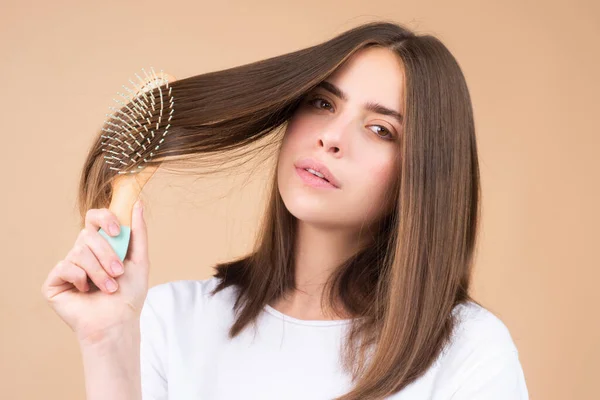 Jonge mooie vrouw kammen haar. Haarverzorging. Mooie brunette haarborstel met haarborstel. Gezond haar borstelen met kam. — Stockfoto