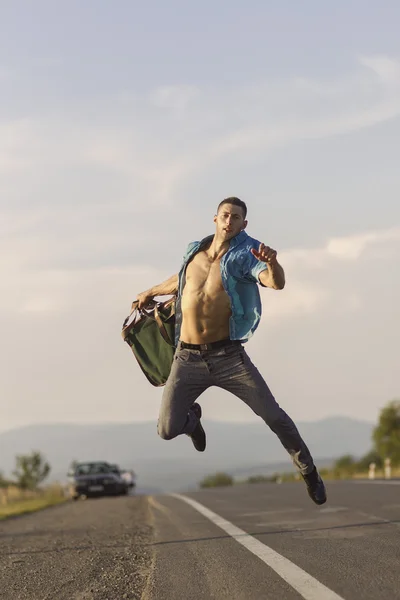 Knappe jonge man springen op de weg — Stockfoto
